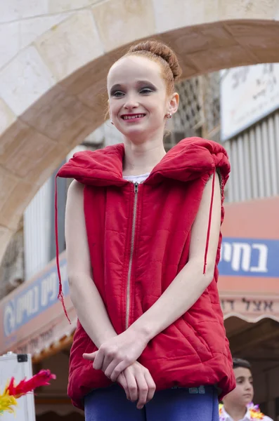 Beer-Sheva, ISRAEL - March 5, 2015: Girl gymnast with red hair in a red jacket without sleeves -Purim