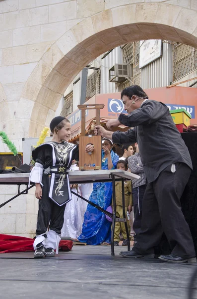 Beer-Sheva, ISRAEL - March 5, 2015: Jewish boy in a black suit and black pile on stage with magician - Purim