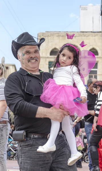 Beer-Sheva, ISRAEL - March 5, 2015: Man with a mustache, in a black and a black cowboy hat and holds a little girl in a pink dress - Purim