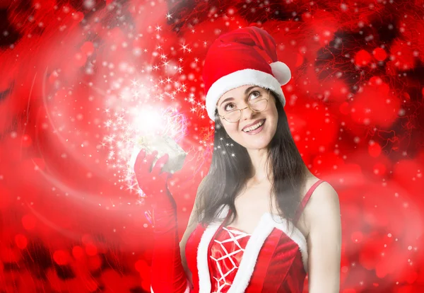 Attractive woman in Santa Claus costume blowing up Christmas wishes.