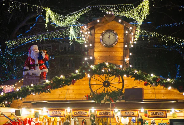 Leicester square traditional fun fair. Decorations with lights, Santa and clock on top of small shop