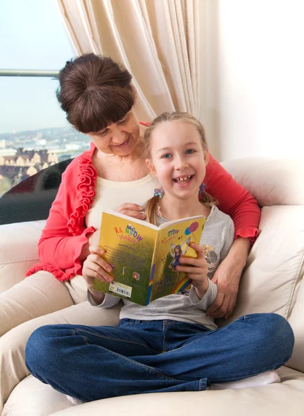 Senior lady with her granddaughter relax together on the the and reading the book