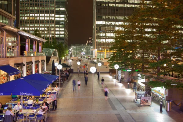 Canary Wharf square view in night lights with office workers chilling out after working day in local cafes and pubs. London