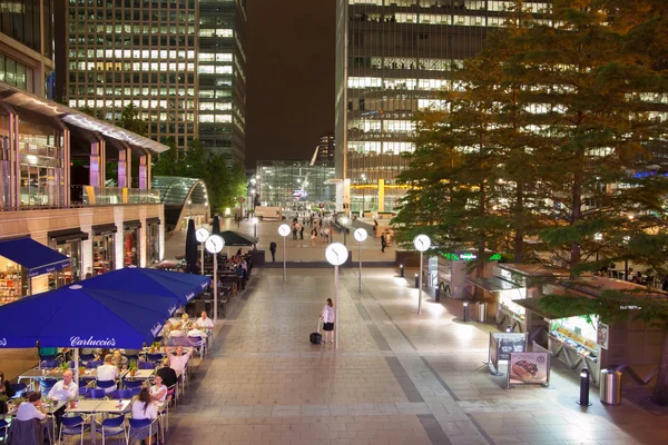 Canary Wharf square view in night lights with office workers chilling out after working day in local cafes and pubs. London