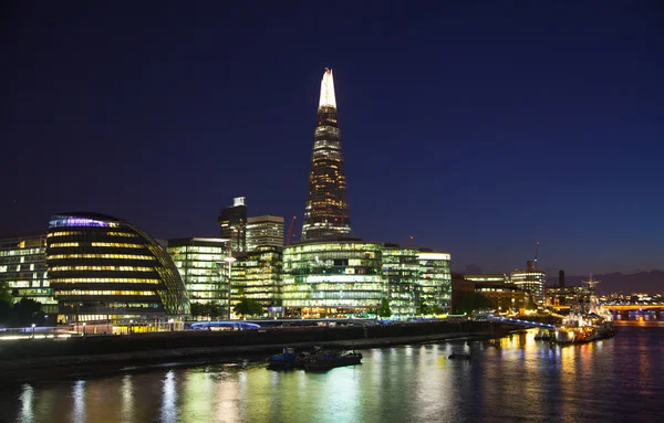 LONDON, UK - AUGUST 11, 2014: South walk of the river Thames in night lights. Modern Buildings view includes London\'s hall and Shard of glass