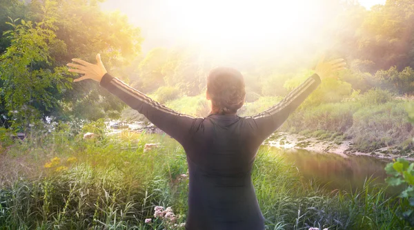 Sunrise, beautiful park and happy woman raising her hands up to the sun. Happy and healthy life concept