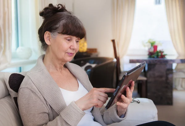 Pension age good looking woman searching in internet on tablet device