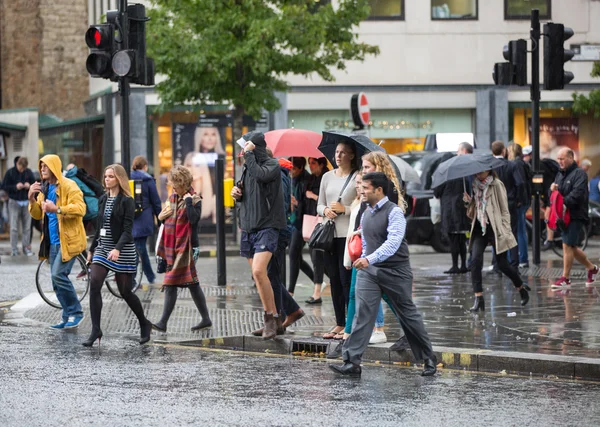 LONDON, UK - SEPTEMBER 17, 2015: Group of people with umbrellas  walking in rain. City of London