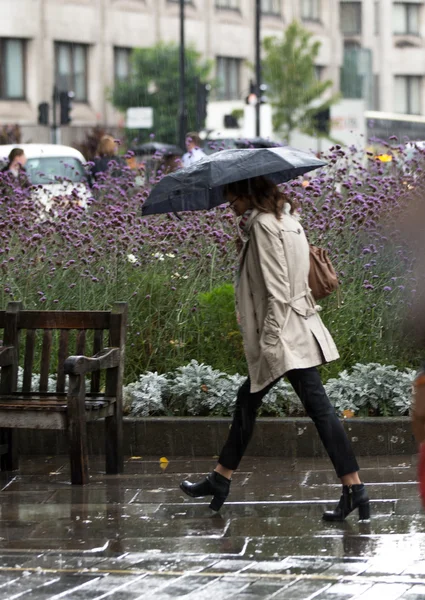 LONDON, UK - SEPTEMBER 17, 2015: Woman with umbrella  walking in rain. City of London