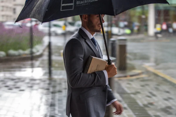 LONDON, UK - SEPTEMBER 17, 2015: Businessman with umbrella  walking in rain. City of London