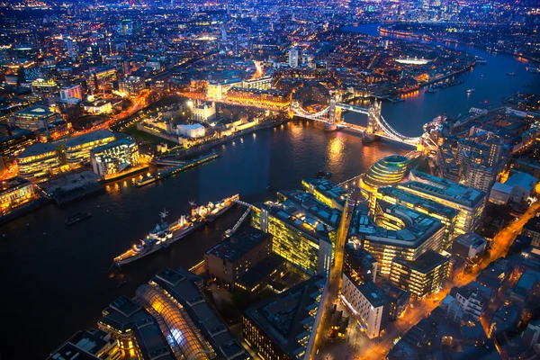 LONDON, UK - APRIL 15, 2015: City of London. Tower bridge night view and well lit up streets aerial view