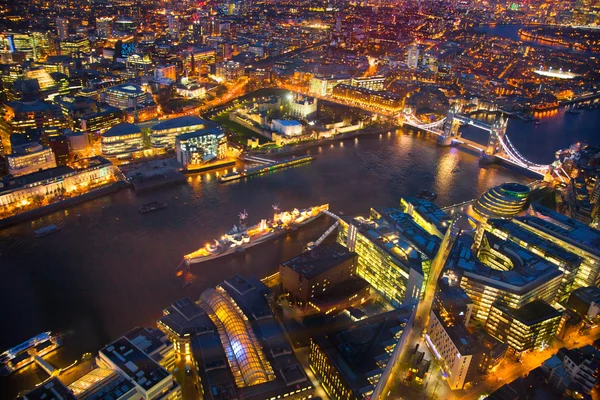 LONDON, UK - APRIL 15, 2015: City of London. Tower bridge night view and well lit up streets aerial view