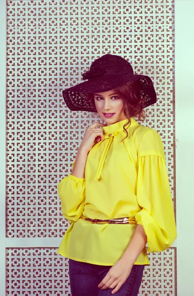 Beautiful girl in a black hat and yellow blouse smiles
