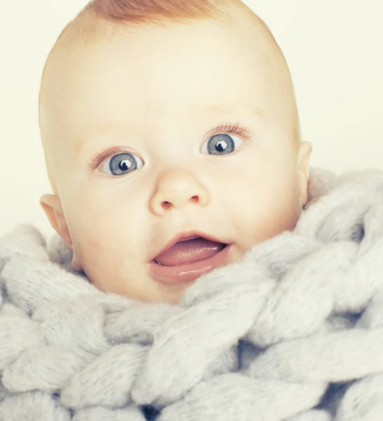 Little cute red head baby in scarf all over him close up isolated, adorable kid winter cold
