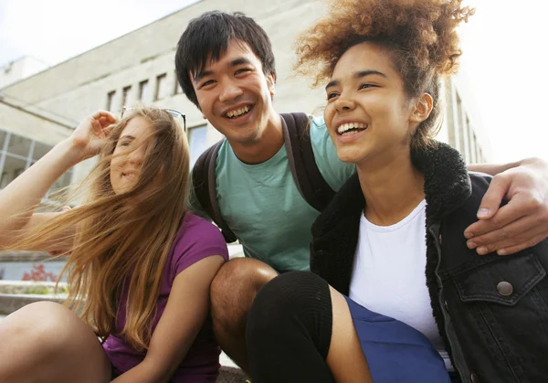 Cute group of teenages at the building of university with books huggings, back to school