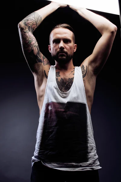 A man with tattooes on his arms. Silhouette of muscular body. caucasian brutal hipster guy with modern haircut, looking like criminal