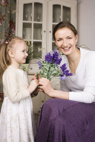 Young mother with daughter at luxury home holding flowers smiling, gift for mummy, lifestyle people concept