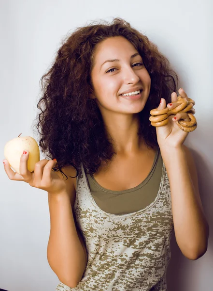Portrait of young cute woman isolated making choice between apple and candys, diet people lifestyle concept
