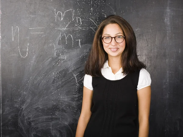 Portrait of happy cute student in classroom at blackboard back to school having fun
