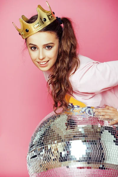 Young cute disco girl on pink background with disco ball and crown