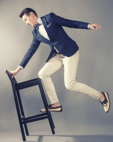 Young handsoman businessman fooling aroung with chair
