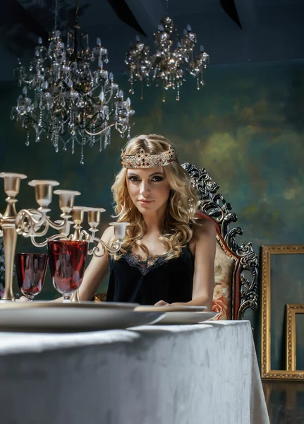 Young blond woman wearing crown in fairy luxury interior with empty antique frames total wealth