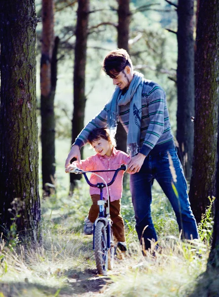 Father learning his son to ride on bicycle outside in park