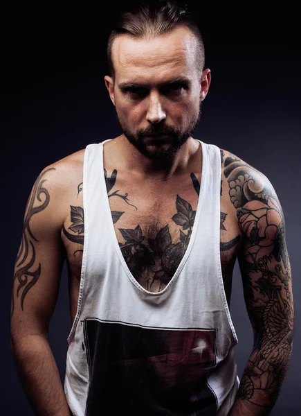 Man with tattooes on his arms. Silhouette of muscular body. caucasian brutal hipster guy  modern haircut, looking like criminal