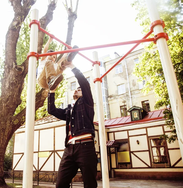 Father with son on playground training, happy real family smiling outside, lifestyle people concept