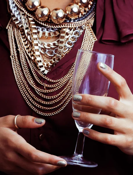 Young african-american woman drinking champagne, holding glass, wearing lot of golden jewelry
