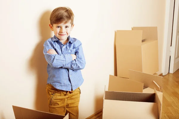 Little cute boy in empty room, remoove to new house. home alone emong boxes