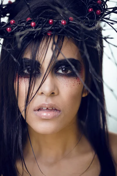 Pretty brunette woman with make up like demon at halloween, closeup scary