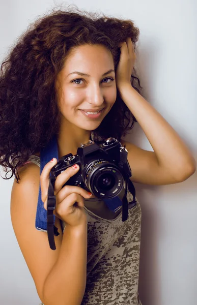 Little cute teenage girl with curly hair holding camera, photographer taking a shot, lifestyle people concept