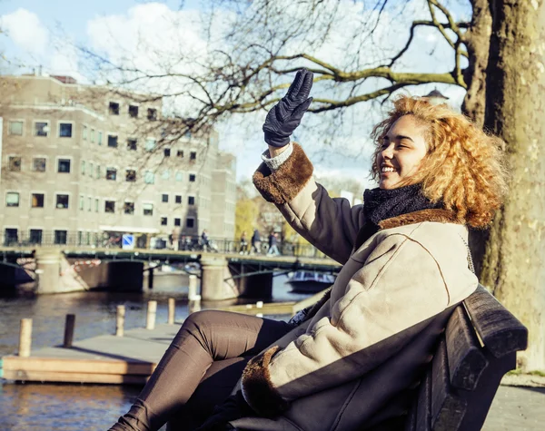 Cute pretty mulatto woman waving and smiling welcoming friends, streets of Amsterdam, lifestyle people concept