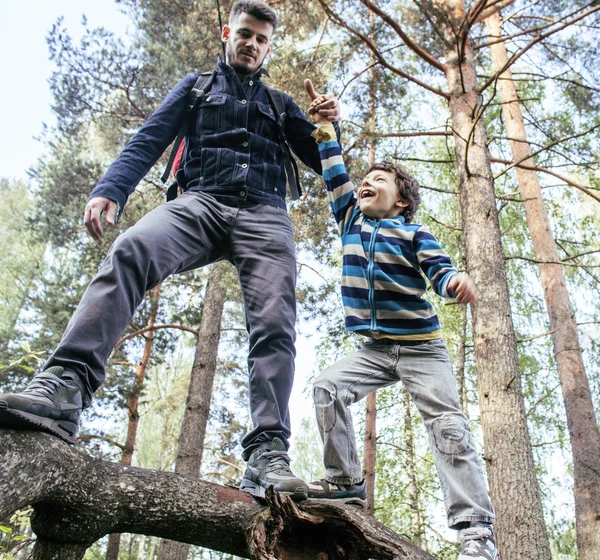 Little son with father climbing on tree together in forest, lifestyle people concept, happy smiling family on summer vacations