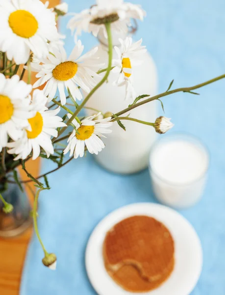 Simply stylish wooden kitchen with bottle of milk and glass on table, summer flowers camomile, healthy food morning concept