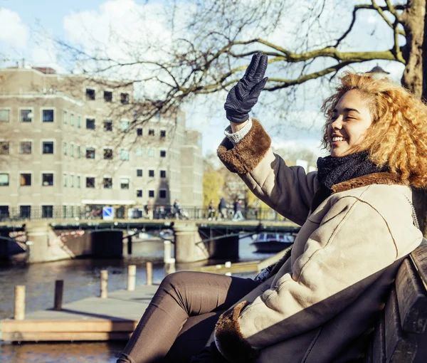 Cute pretty mulatto woman waving and smiling welcoming friends, streets of Amsterdam, lifestyle people concept