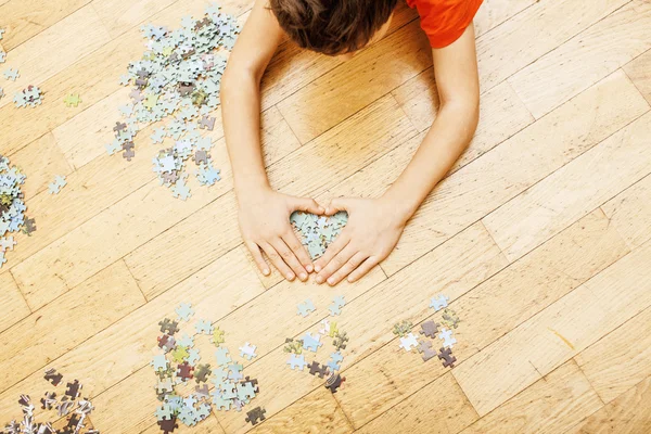 Little kid playing with puzzles on wooden floor together with parent, lifestyle people concept, loving hands to each other