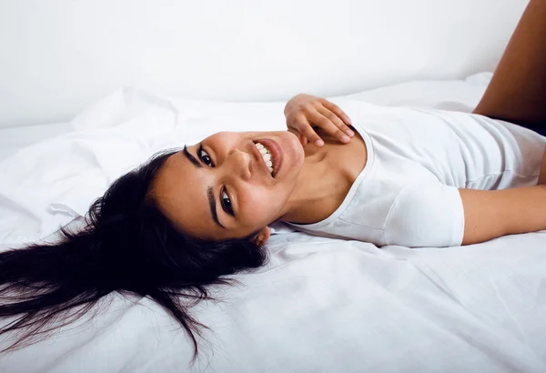 Pretty indian brunette real woman in bed smiling, white sheets, tann skin close up mulatto. cant sleep