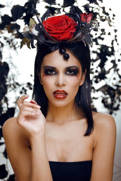 Pretty brunette woman with rose jewelry, black and red, bright make up kike a vampire closeup red lips