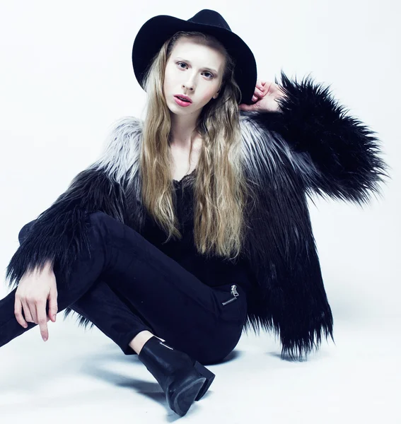 Young blonde teenage girl in hat and fur coat, fashion dressed model, studio shot
