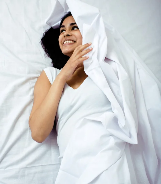 Pretty indian brunette real woman in bed smiling, white sheets, tann skin close up mulatto. cant sleep