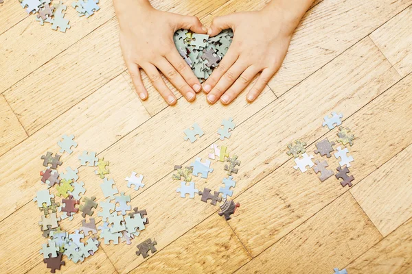 Little kid playing with puzzles on wooden floor together with parent, lifestyle people concept, loving hands to each other