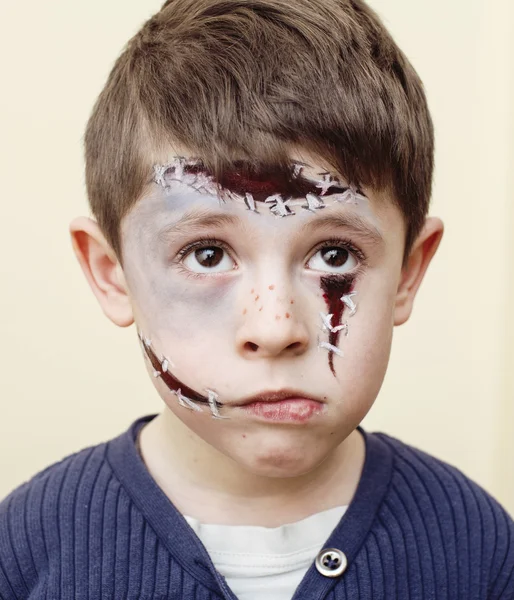 Little cute boy with facepaint like zombie apocalypse at halloween party close up, treat or treat people concept