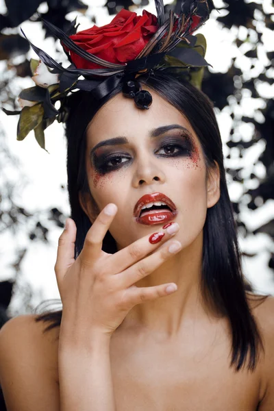 Pretty brunette woman with rose jewelry, black and red, bright make up kike a vampire closeup red lips