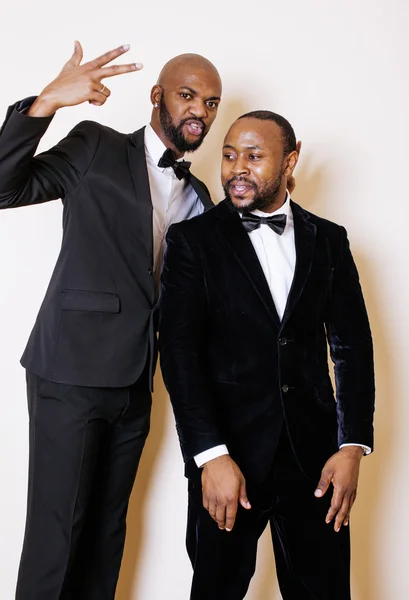 Two afro-american businessmen in black suits emotional posing, gesturing, smiling. wearing bow-ties