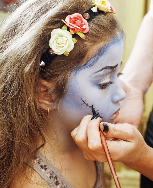 Little cute child making facepaint on birthday party, zombie Apocalypse facepainting, halloween preparing concept, lifestyle people