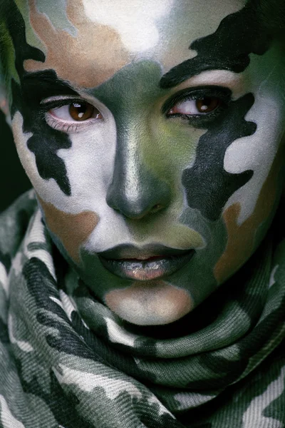 Beautiful young fashion woman with military style clothing and face paint make-up, khaki colors, halloween celebration close up, green pattern