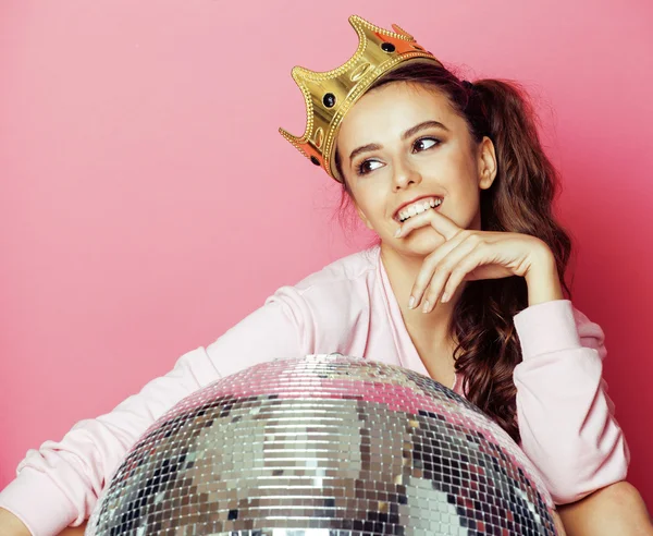 Young cute disco girl on pink background with disco ball and crown