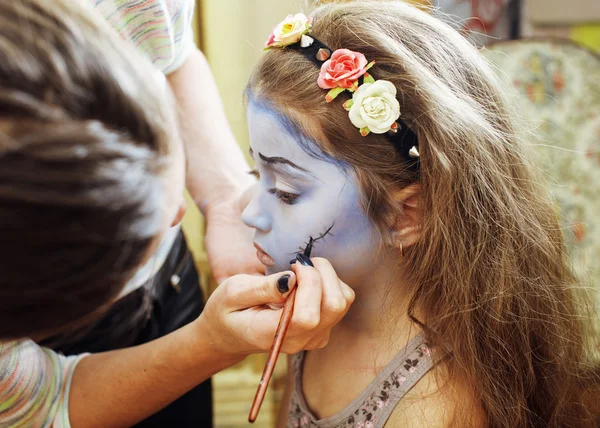 Little cute child making facepaint on birthday party, zombie Apocalypse facepainting, halloween preparing concept